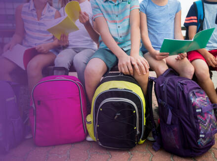 Students sit together with backpacks and school materials, representing a school setting and student participation